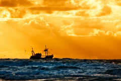 vissersschip op zee bij zonsondergang