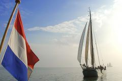 zeilboot met op voorgrond de Nederlandse vlag